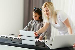 söt liten flicka spelar på piano, synthesizer. Träning. utbildning. skola. estetisk Träning. elementärt klassrum. foto