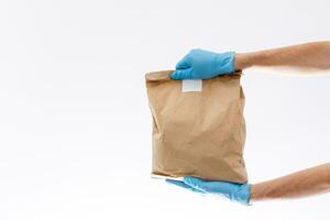 Hem leverans, uppkopplad ordning. en man i enhetlig, en medicinsk mask och sudd handskar med en låda, en paket i hans händer. mat och mat leverans under de karantän av de coronavirus pandemi foto