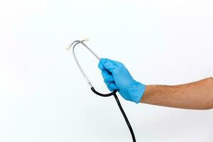 stänga upp av kvinna läkares hand i blå steriliseras kirurgisk handske med stetoskop mot vit bakgrund foto