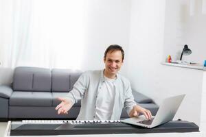 en man inlärning till spela piano uppkopplad med en dator vistas på Hem. begrepp av själv lärde, vistas på Hem och arbetssätt uppkopplad foto