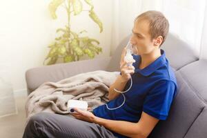 porträtt av ung man andas in genom inhalator mask foto