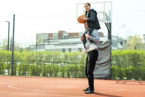 far och Tonårs dotter spelar basketboll utanför på domstol foto