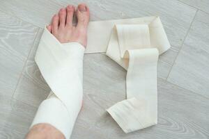 man använder sig av sätta på elastisk bandage med ben har ben smärta foto