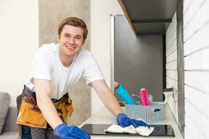 ung glad man rengöring kök smutsig hushåll plikt spray flaska damm inomhus foto