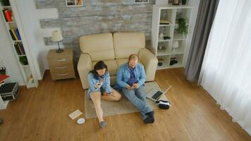 topp se av caucasian par i denim bläddring på smartphone på de golv av deras lägenhet foto