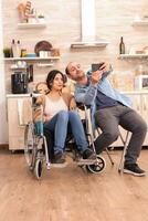romantisk man tar selfie med Inaktiverad fru i rullstol. Inaktiverad lam handikappade kvinna med gående handikapp integrering efter ett olycka. foto
