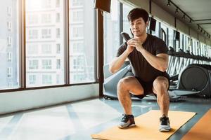 sport man gör squat hållning på yogamatta i fitness gym på bostadsrätt i urban. människors livsstil och sportträningskoncept foto