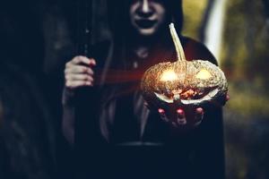 pumpa i häxhand. gammal kvinna som håller pumpa i mörk skog. halloween dag och mysterium koncept. fantasi om magiskt tema foto
