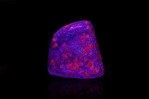 makro mineral sten rubin under ultraviolett ljus på en svart bakgrund foto