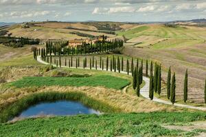 känd tuscany landskap med böjd väg och cypress, Italien, Europa. lantlig odla, cypress träd, grön fält, solljus och moln. foto