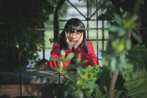 asiatisk tonåring bär röd Tröja Sammanträde utomhus- foto
