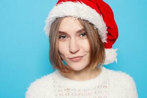 Söt blond bär jul hatt på ljus blå bakgrund foto