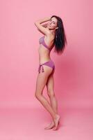förtjusande brunett i bikini Framställ på rosa bakgrund foto