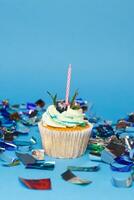 födelsedag muffin med tre brinnande ljus över blå bakgrund foto