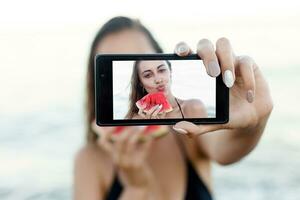 sommar semester - ung flicka äter färsk vattenmelon på sandig strand foto