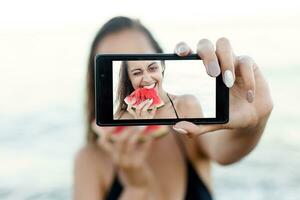 sommar semester - ung flicka äter färsk vattenmelon på sandig strand foto