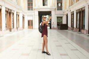 porträtt av skön ung turist kvinna innehav upp en smartphone tar selfies foto