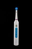 en vit elektrisk tandborste med blå och lila knappar foto