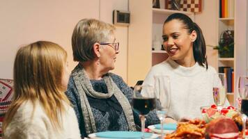 mormor talande med henne dotter och barnbarn på familj återförening för jul firande. traditionell festlig jul middag i flera generationer familj. njuter xmas måltid fest i dekorerad rum. stor familj återförening foto