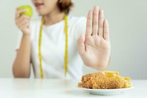 skönhet smal kvinna kropp förvirra franska frites och friterad kyckling. kvinna i restaurang uppnår vikt förlust mål för friska liv, galen handla om tunnhet, tunn midja, nutritionist. diet, kropp form. foto