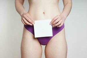 kvinna i trosor innehav tom bit av papper med kopia Plats över genital område foto