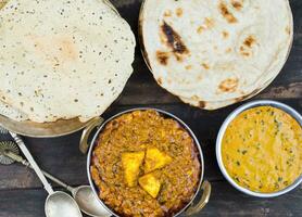 indisk mat kadai paneer eras med dal makhani, tandoori eller papad på trä- bakgrund foto