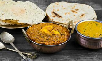 indisk mat kadai paneer eras med dal makhani, tandoori eller papad på trä- bakgrund foto