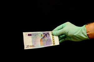 en hand i en handske innehav en tjugo euro Bank notera foto
