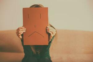 deprimerad kvinna Sammanträde ensam på soffa och innehav papper med ledsen ansikte.tonad bild. foto