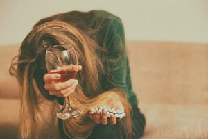 deprimerad kvinna dricka alkohol medan Sammanträde ensam på soffa.tonad bild. foto