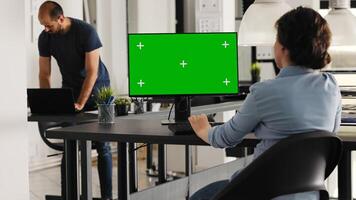 affärskvinna Arbetar med grönskärm på pc skrivbord, Sammanträde i coworking Plats på byrå kontor. ung vuxen anställd granskning dator övervaka den där visar isolerat visa med chromakey. foto