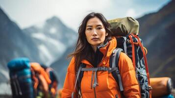 ai genererad ett asiatisk kvinna äventyrare i vibrerande orange ytterkläder står redo med en ryggsäck, uppsättning mot en dramatisk berg landskap, anda av utforskning. foto