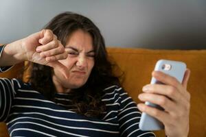 medelålders kvinna använder sig av smartphone för video ringa upp, som visar tummen ner foto