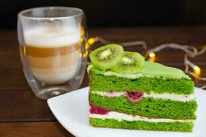 pistasch kaka med kiwi, grädde och hallon fyllning och cappuccino kaffe foto