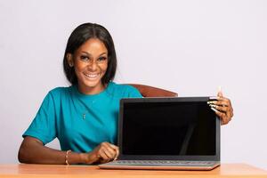 porträtt av en skön ung svart kvinna som visar henne bärbar dator skärm foto