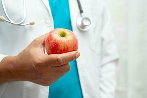 läkare innehav äpple frukt vitamin mat för friska patient i sjukhus. foto
