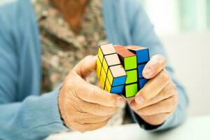 Bangkok, thailand augusti 14, 2023 alzheimers sjukdom annons, asiatisk äldre kvinna patient spelar rubik kub spel till öva hjärna Träning för demens förebyggande. foto