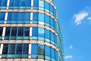 glas byggnad med transparent Fasad av de byggnad och blå himmel. strukturell glas vägg reflekterande blå himmel. foto