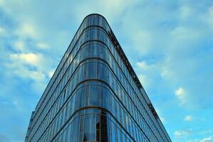 glas byggnad med transparent Fasad av de byggnad och blå himmel. strukturell glas vägg reflekterande blå himmel. abstrakt modern arkitektur fragment. samtida arkitektonisk bakgrund. foto