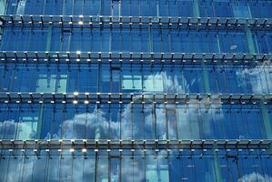 glas byggnad med transparent Fasad av de byggnad och blå himmel. strukturell glas vägg reflekterande blå himmel. abstrakt modern arkitektur fragment. samtida arkitektonisk bakgrund. foto