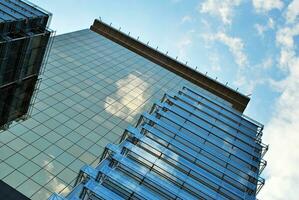 glas byggnad med transparent Fasad av de byggnad och blå himmel. strukturell glas vägg reflekterande blå himmel. abstrakt modern arkitektur fragment. samtida arkitektonisk bakgrund. foto