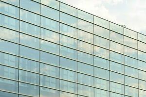 glas byggnad med transparent Fasad av de byggnad och blå himmel. strukturell glas vägg reflekterande blå himmel. abstrakt modern arkitektur fragment. samtida arkitektonisk bakgrund. foto