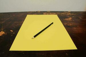 en penna Sammanträde på topp av en gul ark av papper foto