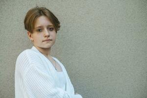 Tonårs flicka kort röd hår kontraster med lugn uttryck i en porträtt fångar väsen av ungdom foto