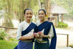 närbild en skön två thai ung kvinnor gods thai nordlig traditionell klänning verkande för Foto skjuta i offentlig parkera och suddig bakgrund.