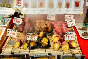 osaka stad, Japan, 2019 - japansk ljuv potatis skiva och ånga på bambu grill med japansk namn och pris etiketter. sälja i kuromon mat marknadsföra. populär till uppäten i de vinter. foto