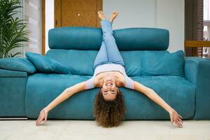 Lycklig kvinna kvinna liggande upside ner på soffa på Hem foto