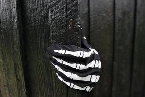 svart trädörr och svart handske med detaljer av mänskligt skelettprydnad. foto