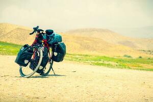 touring cykel stå på naturskön grus väg i natur. fullt lastad touring maskin med kopia Plats bakgrund foto