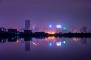 en stad som reflekteras av sjön på natten foto